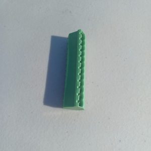 A Header Terminal Blocks 12 Position lies on a white surface, casting a shadow to the left.