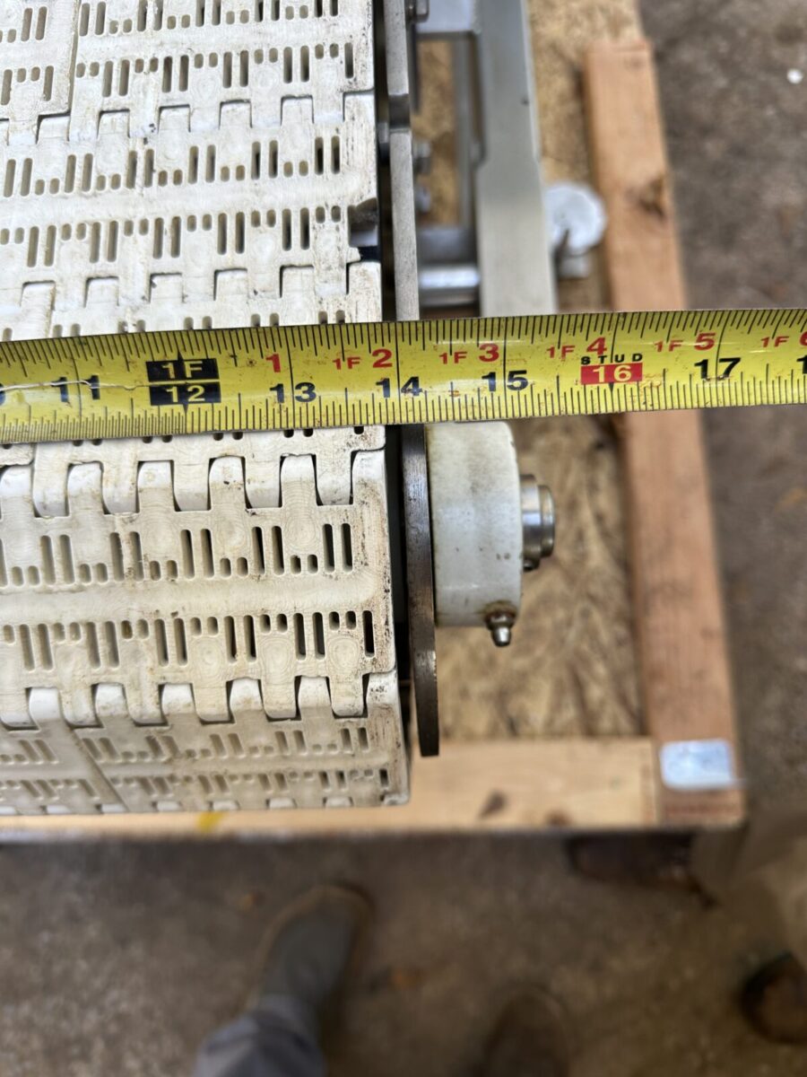 A tape measure shows the Fortress Belt Stop Conveyor L13899 has a belt width of about 14.5 inches on a wooden frame.