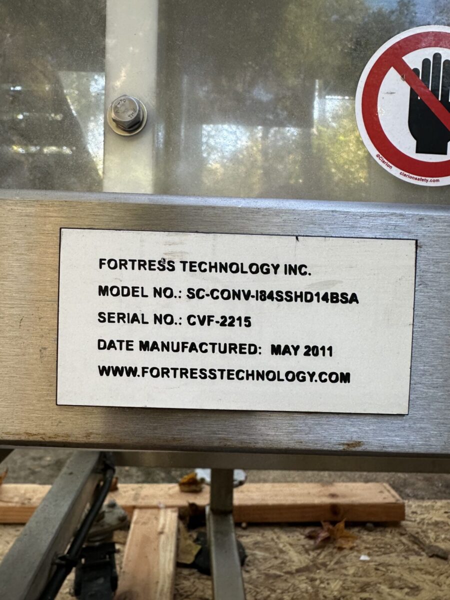 Label on equipment shows Fortress Belt Stop Conveyor L13899, serial number, manufacture date, and website.