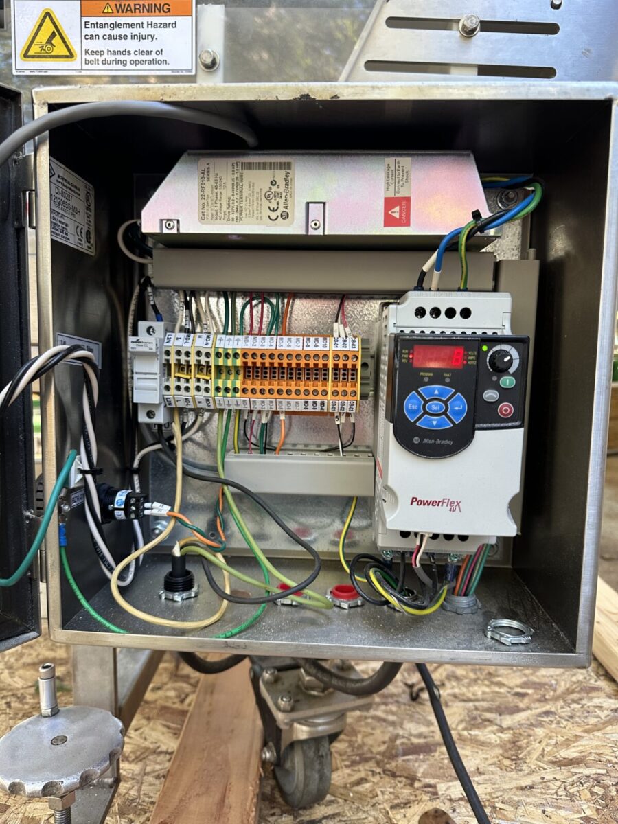 Open electrical control panel with exposed wires, terminal blocks, and Fortress Belt Stop Conveyor L13899, warning labels visible.