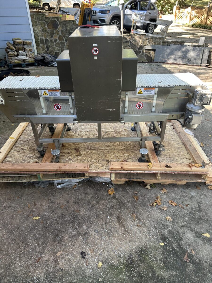 Fortress Belt Stop Conveyor L13899 on a wooden pallet outdoors with visible warning labels on the machine.